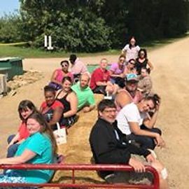 People sitting on a hayride wagon on a farm.