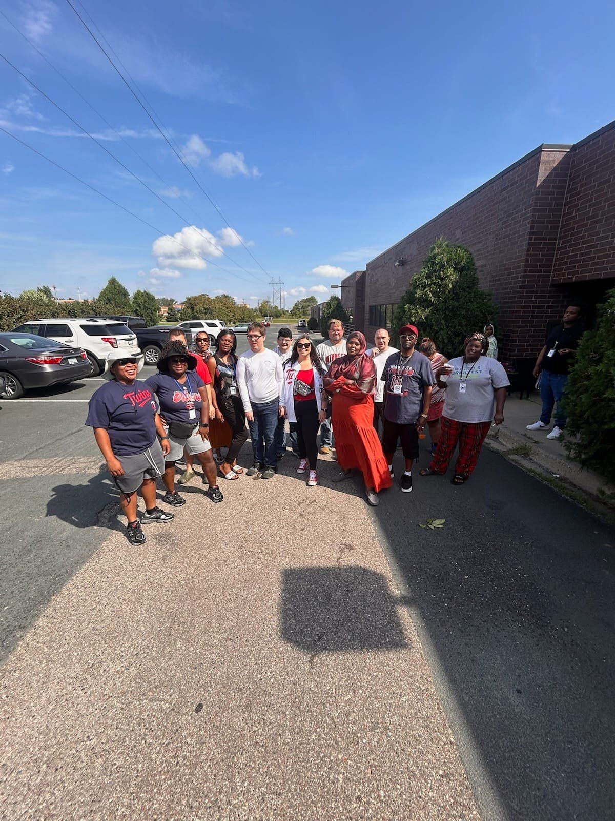 Group of people walking on a gravel path near a building on a sunny day.