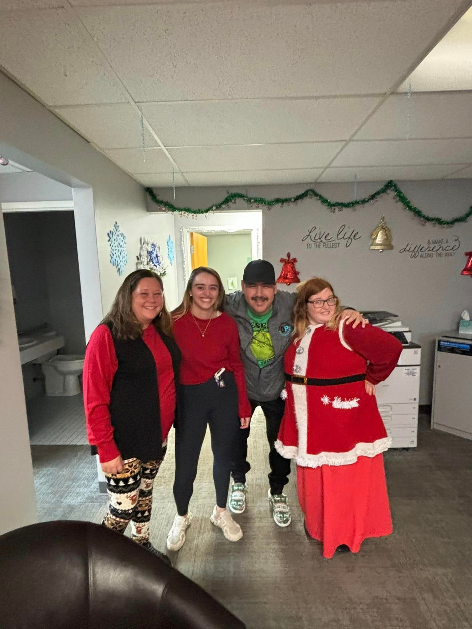 Four people in festive attire posing indoors with holiday decorations.