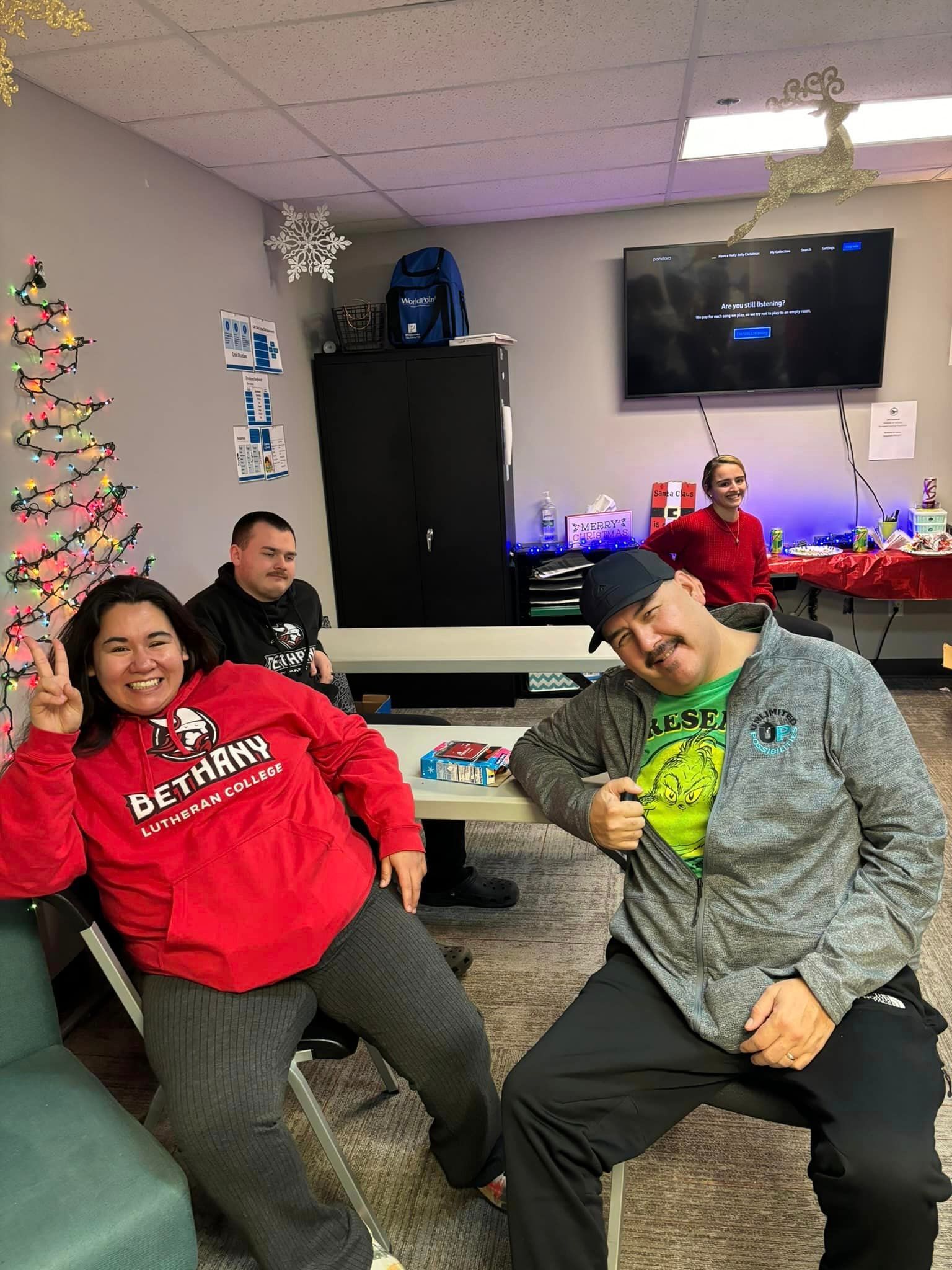 People at a holiday gathering; two smiling, one giving peace sign.