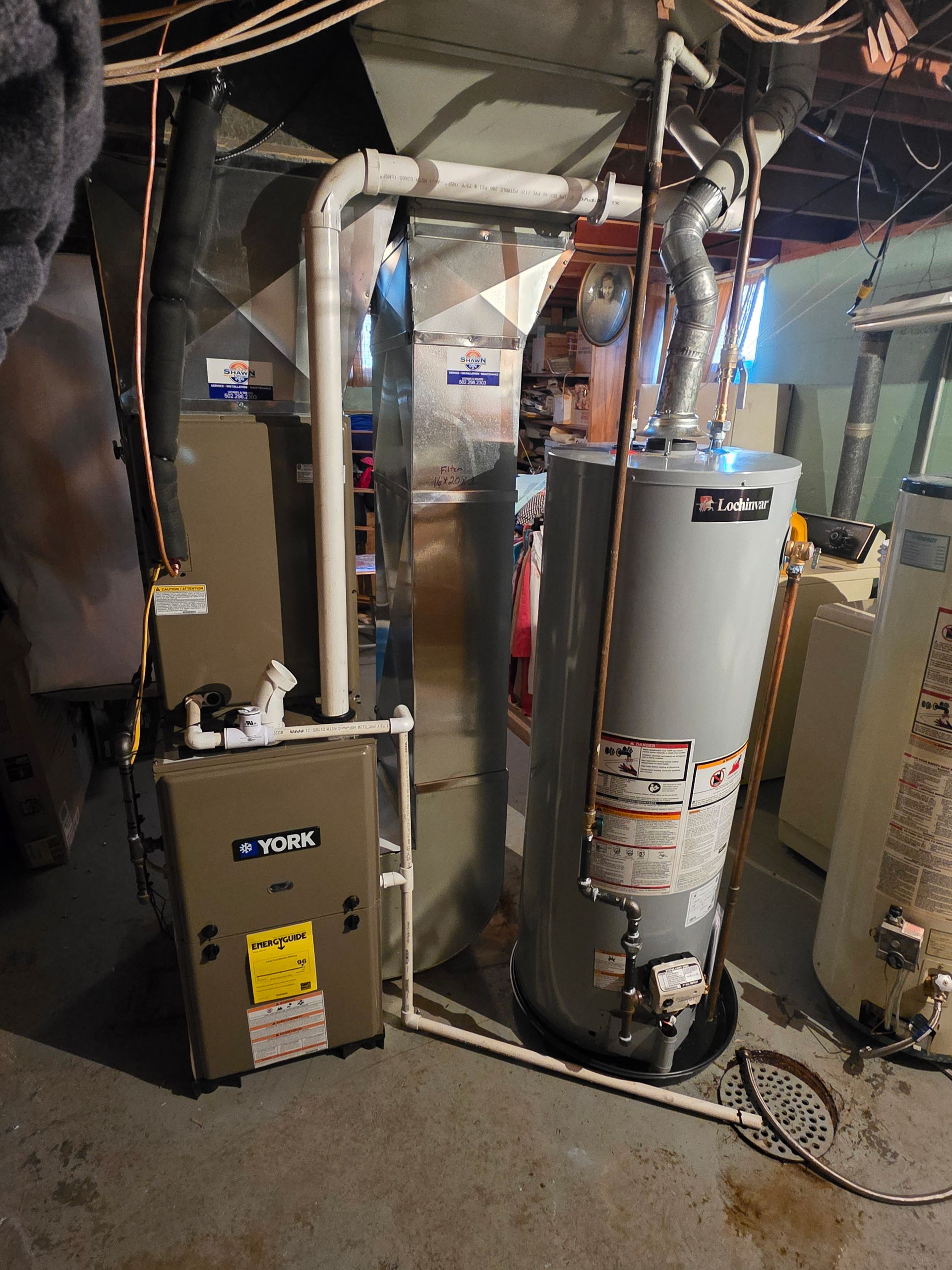 A water heater is sitting next to a furnace in a basement.