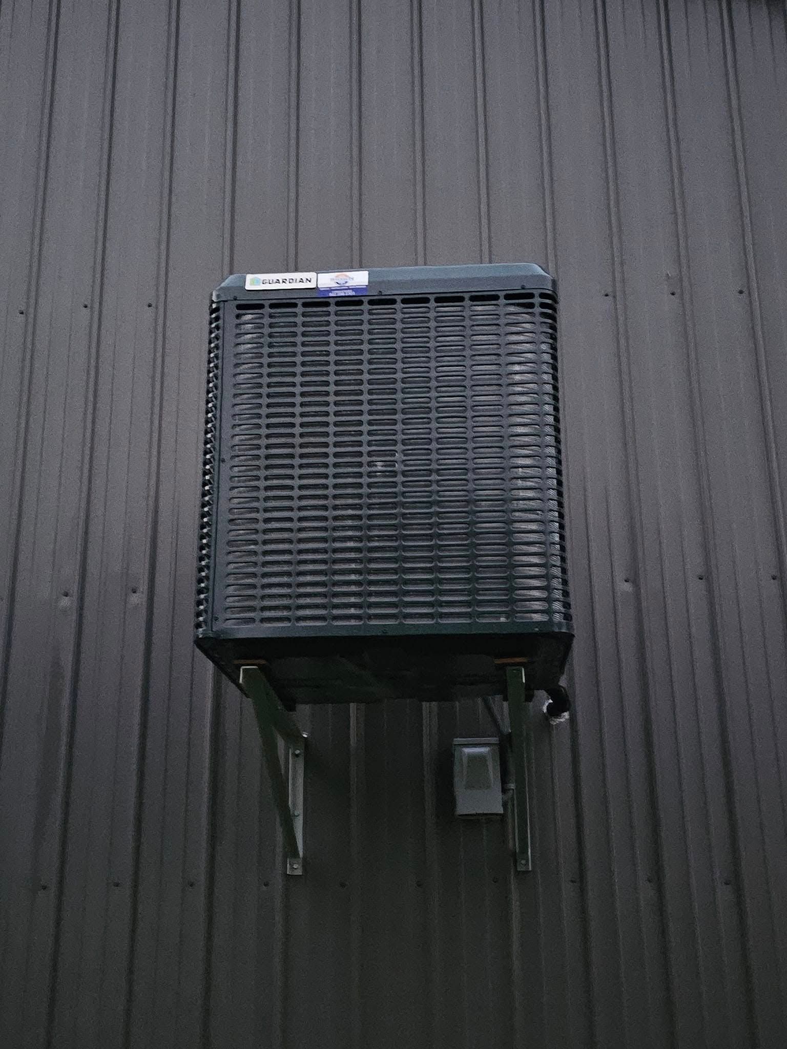 Black evaporative cooler mounted on dark grey siding.