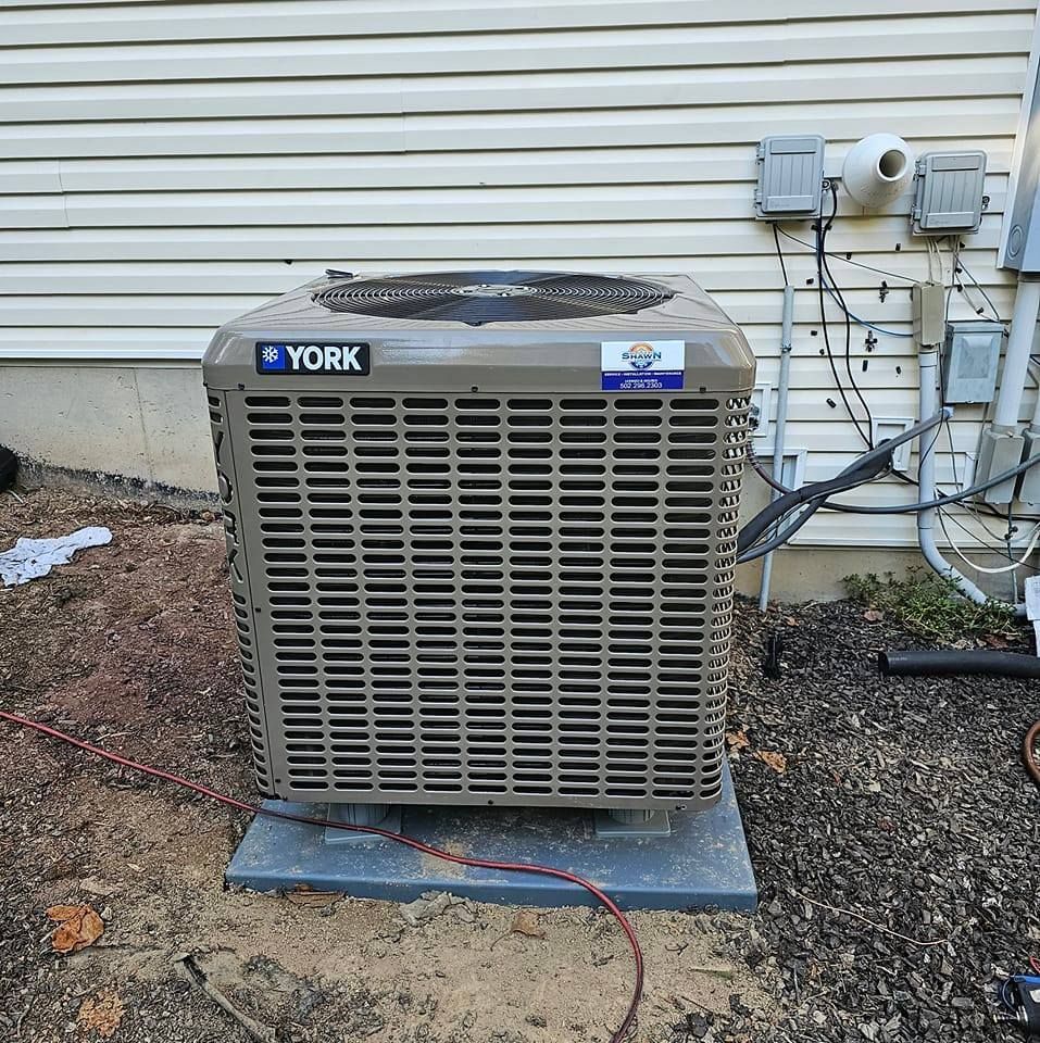A york air conditioner is sitting outside of a house.