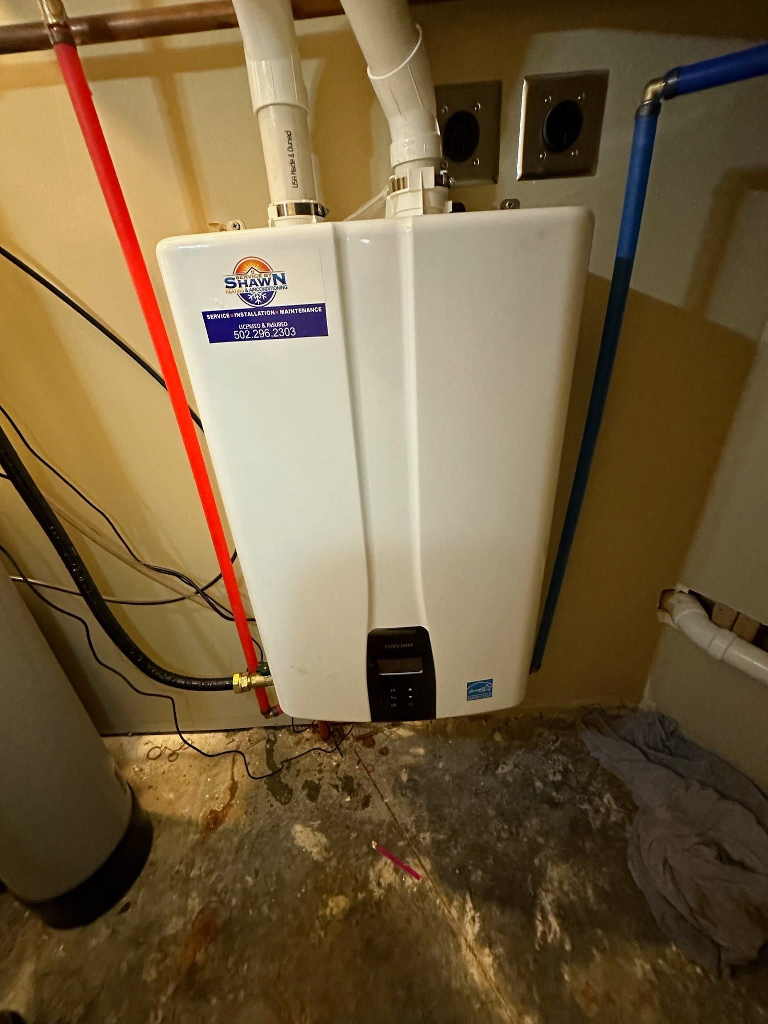 A white water heater is hanging from the ceiling in a room.