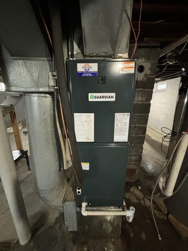 An air conditioner is hanging from the ceiling in a basement.