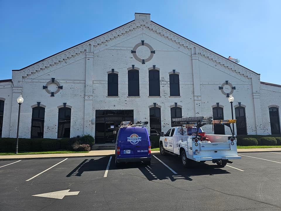 Two trucks are parked in front of a large white building.