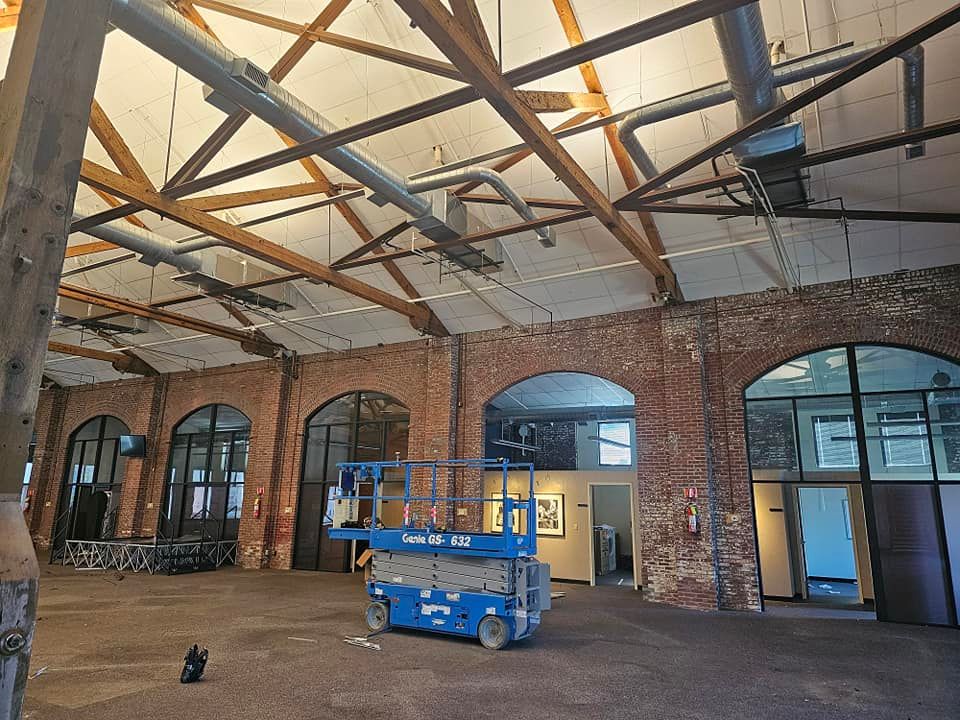 A blue scissor lift is parked in an empty building