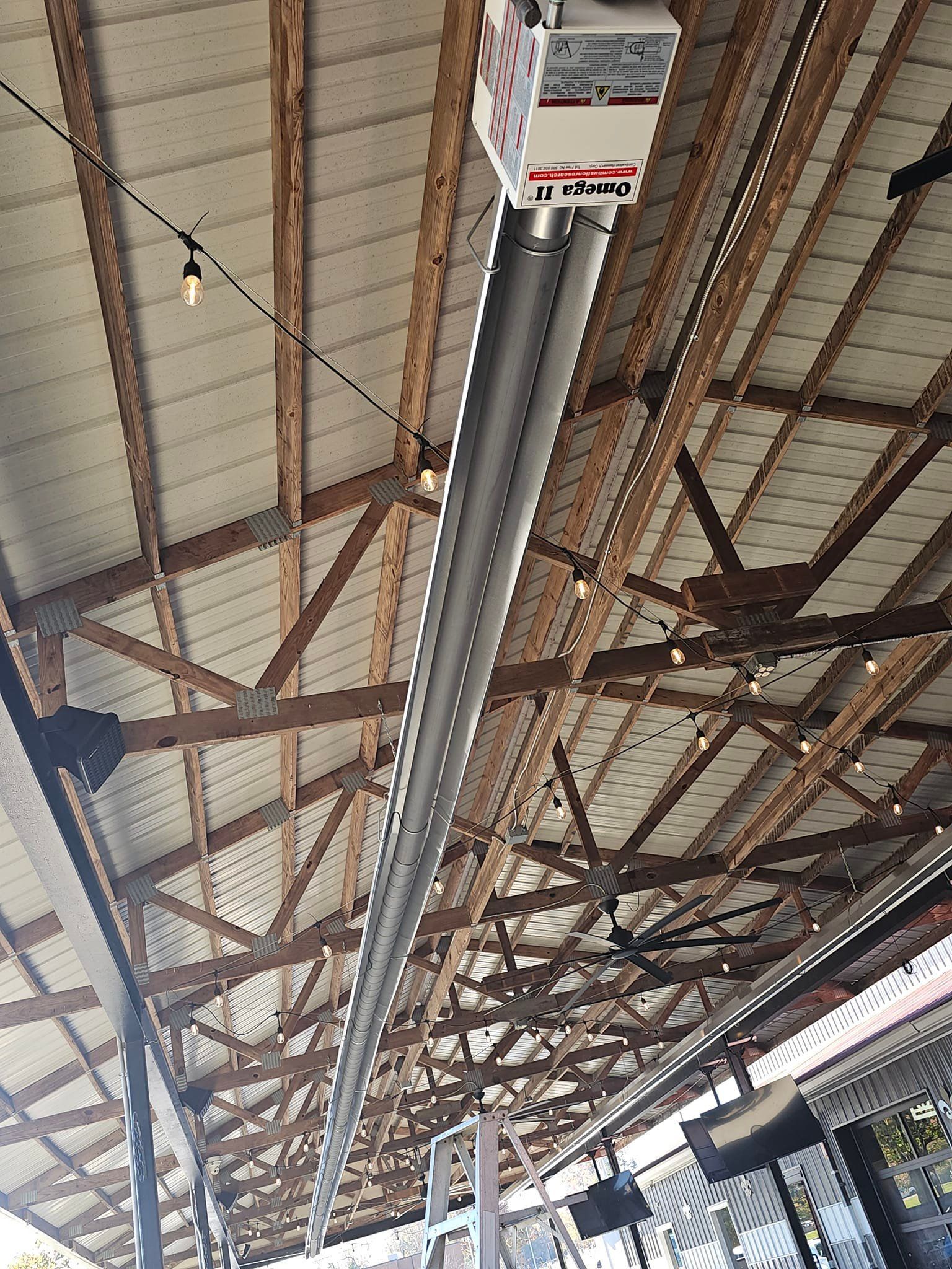 A large heater is hanging from the ceiling of a building.
