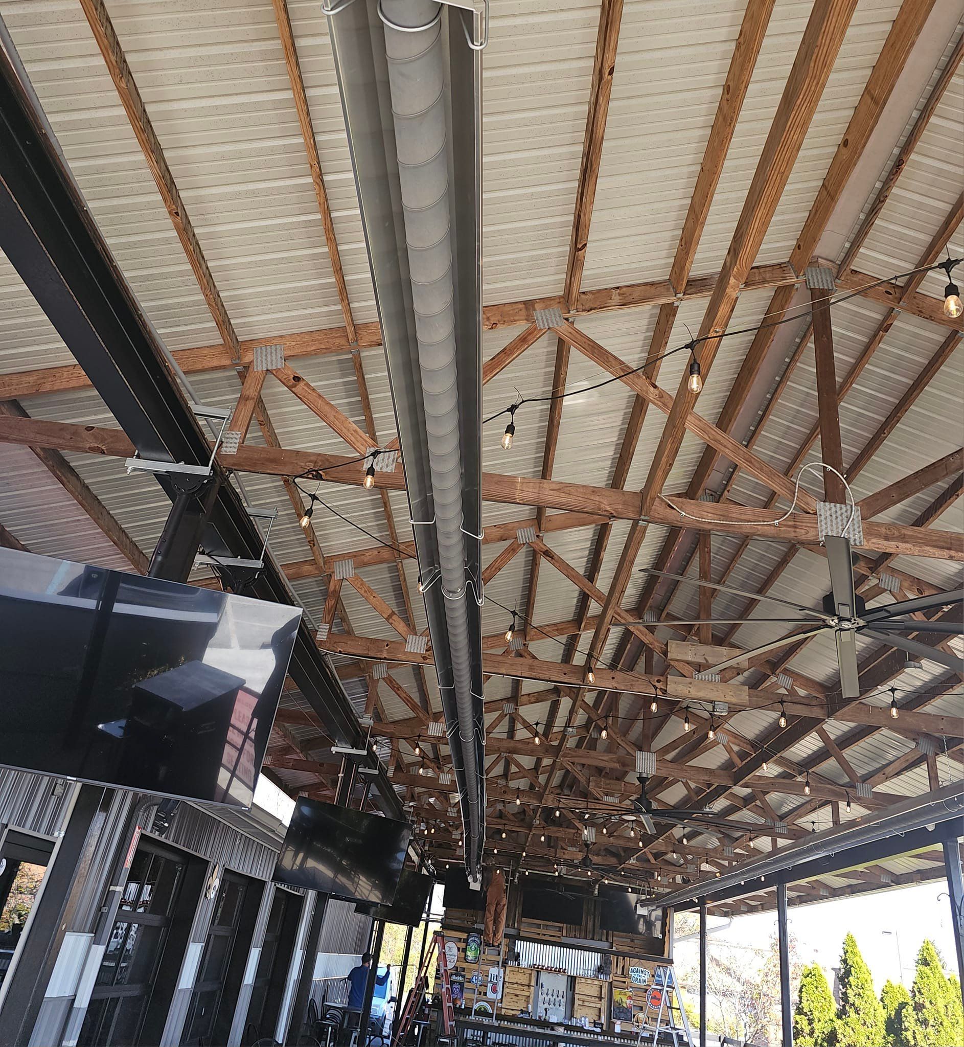 The ceiling of a building with wooden beams and a ceiling fan.
