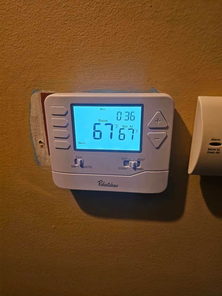 A thermostat is sitting on a wall next to a smoke detector.