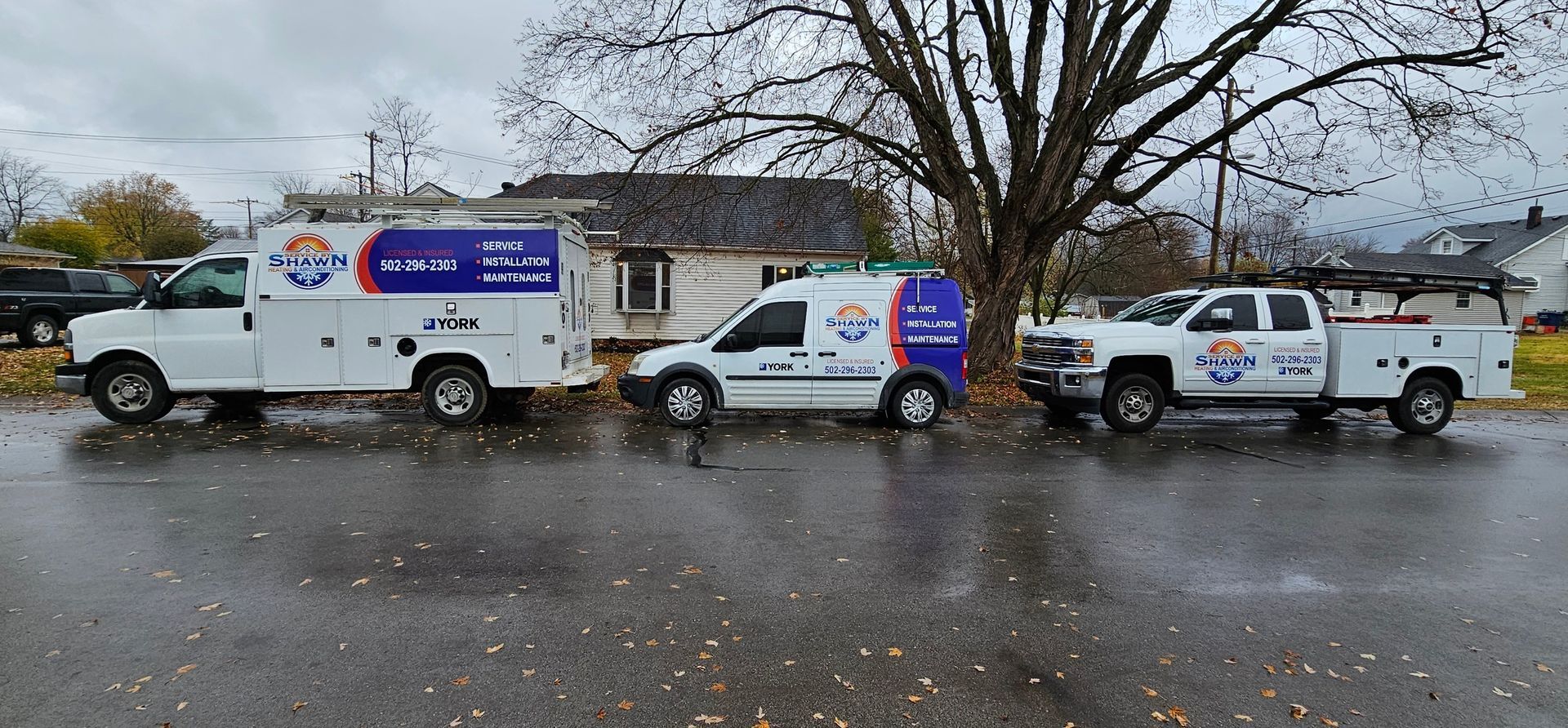 Three trucks are parked on the side of the road in front of a house.