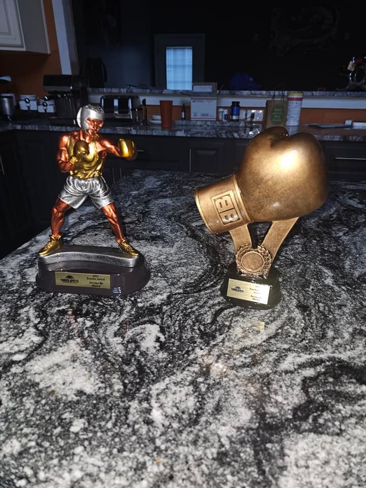 A statue of a boxer and a boxing glove are on a counter.