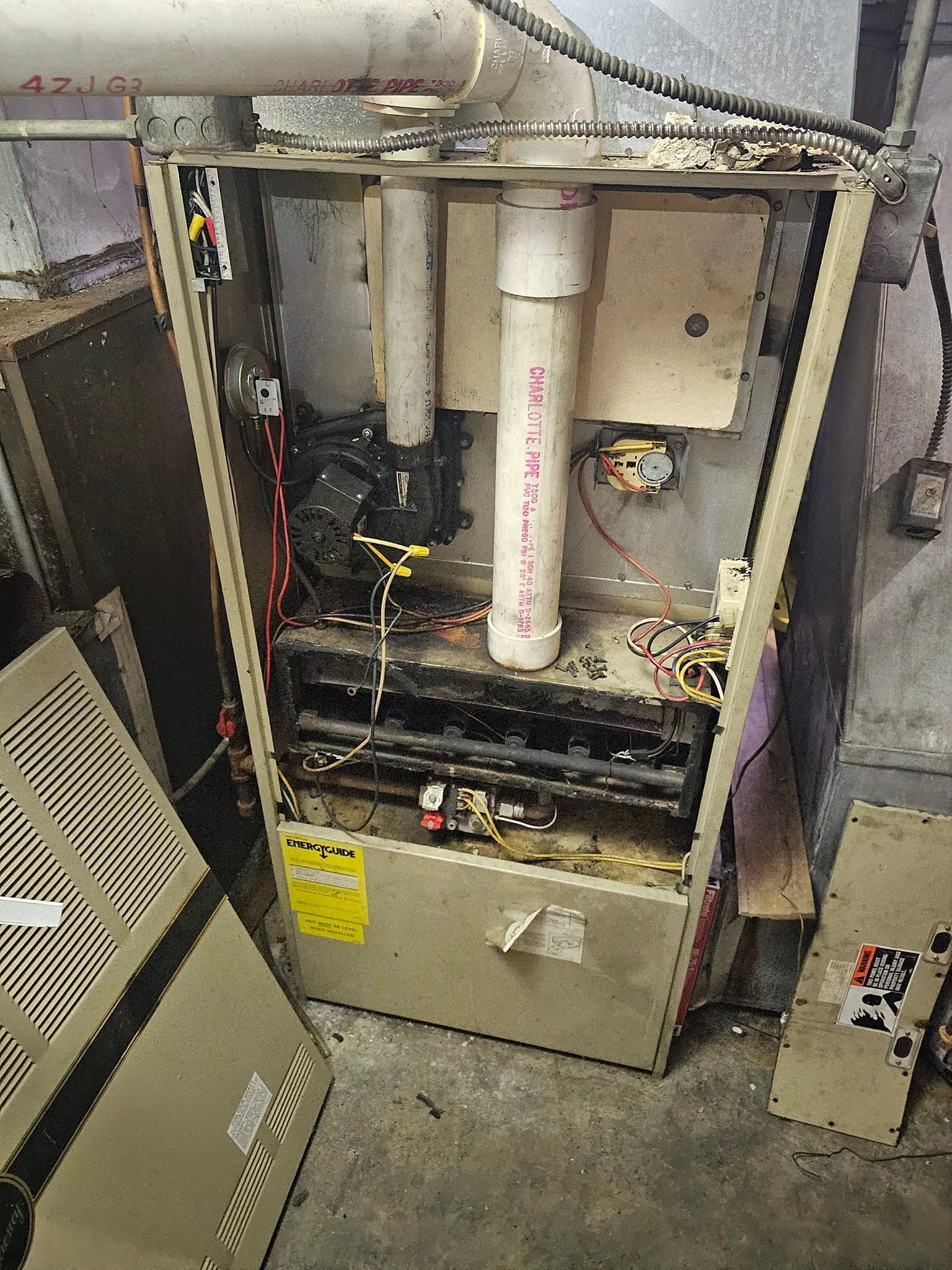 A broken air conditioner is sitting on the floor in a garage.