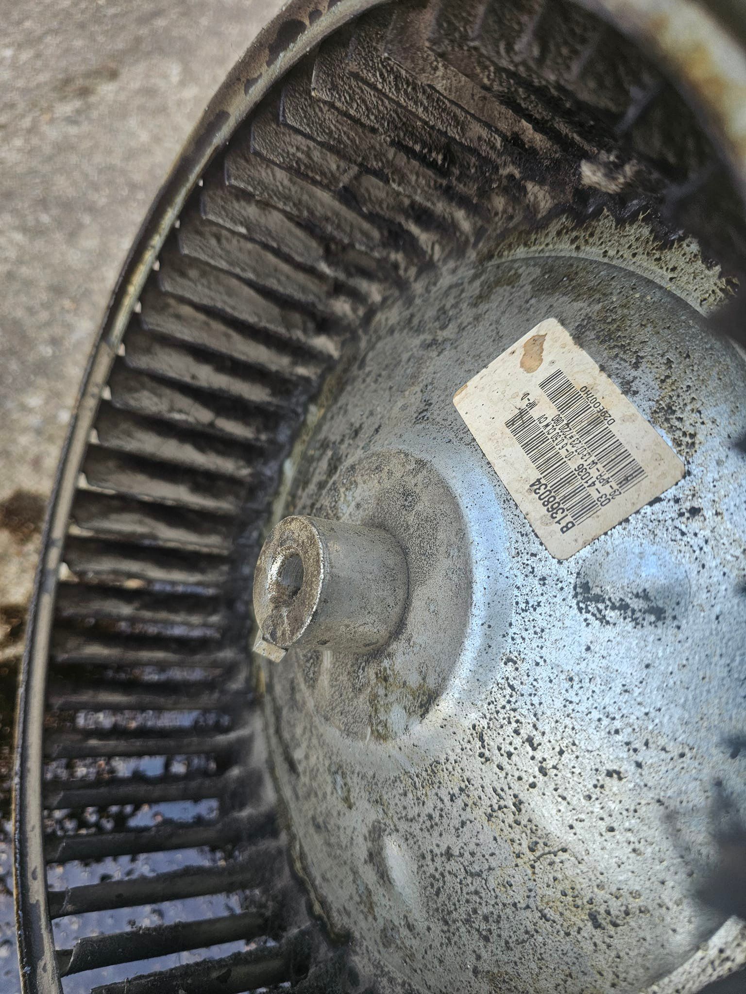A close up of a dirty blower wheel with a tag on it.