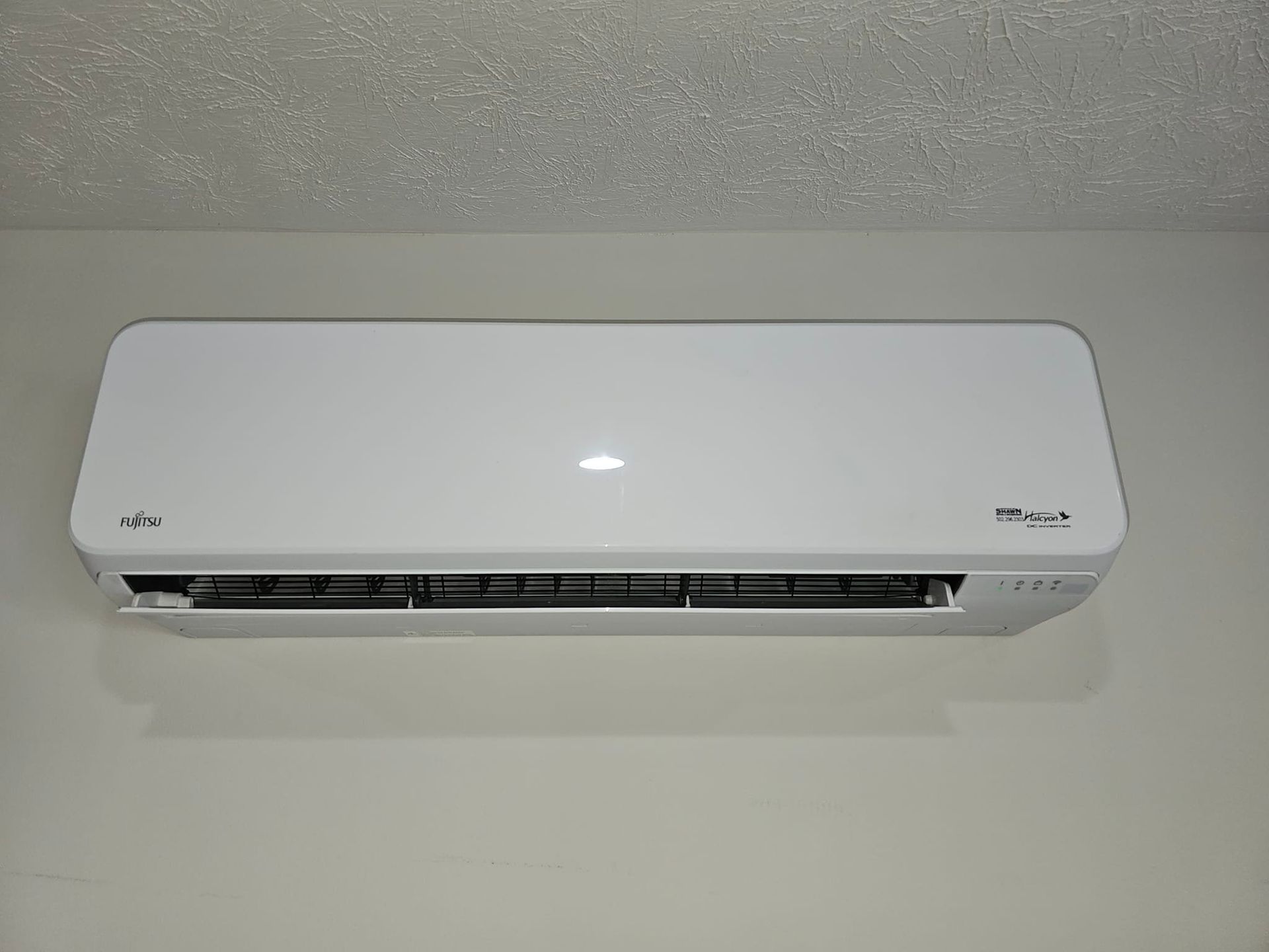 A white air conditioner is hanging on a white wall.