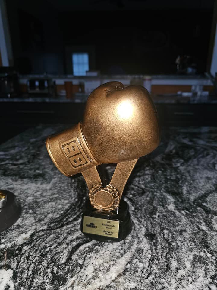 A gold boxing glove trophy is sitting on a table.