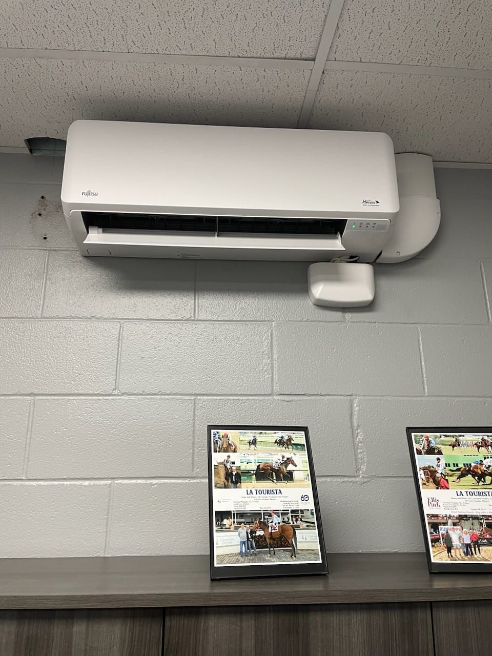 A white air conditioner is mounted on a brick wall