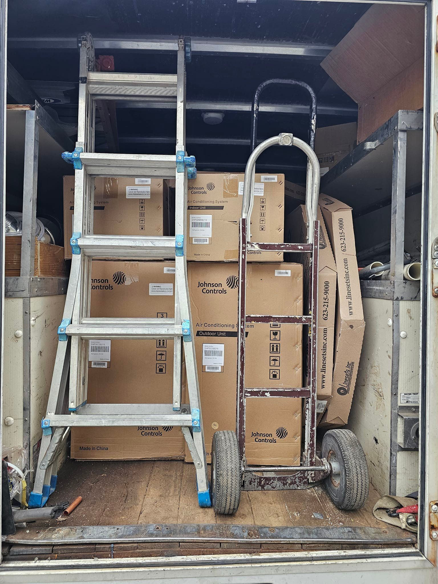 A ladder and a hand truck are in the back of a truck