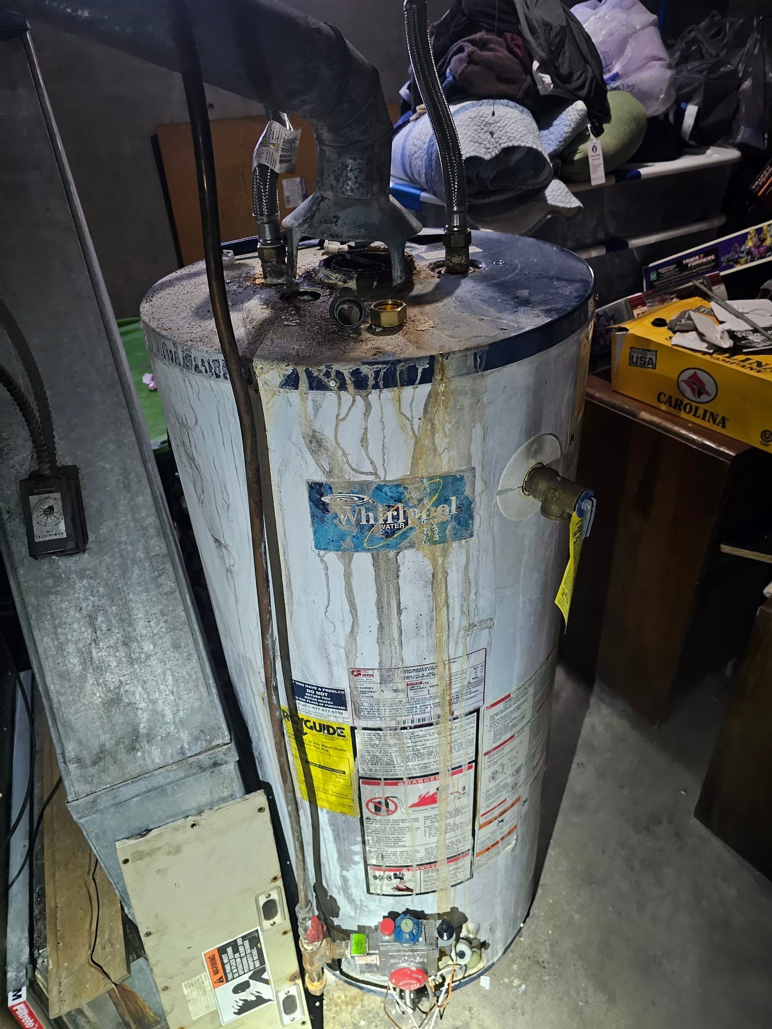 A dirty water heater is sitting in a messy room.