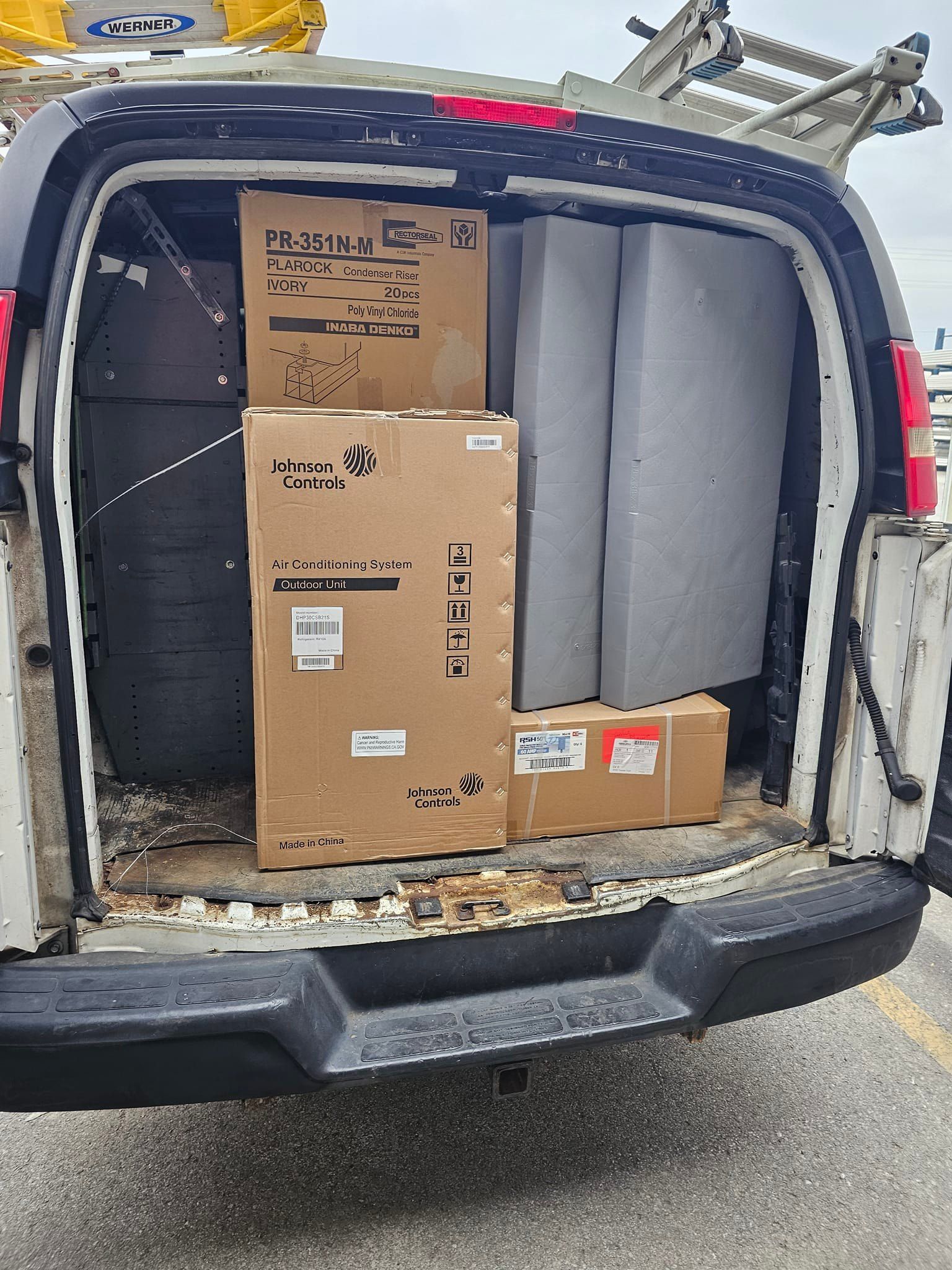 The back of a van is filled with boxes and cushions.