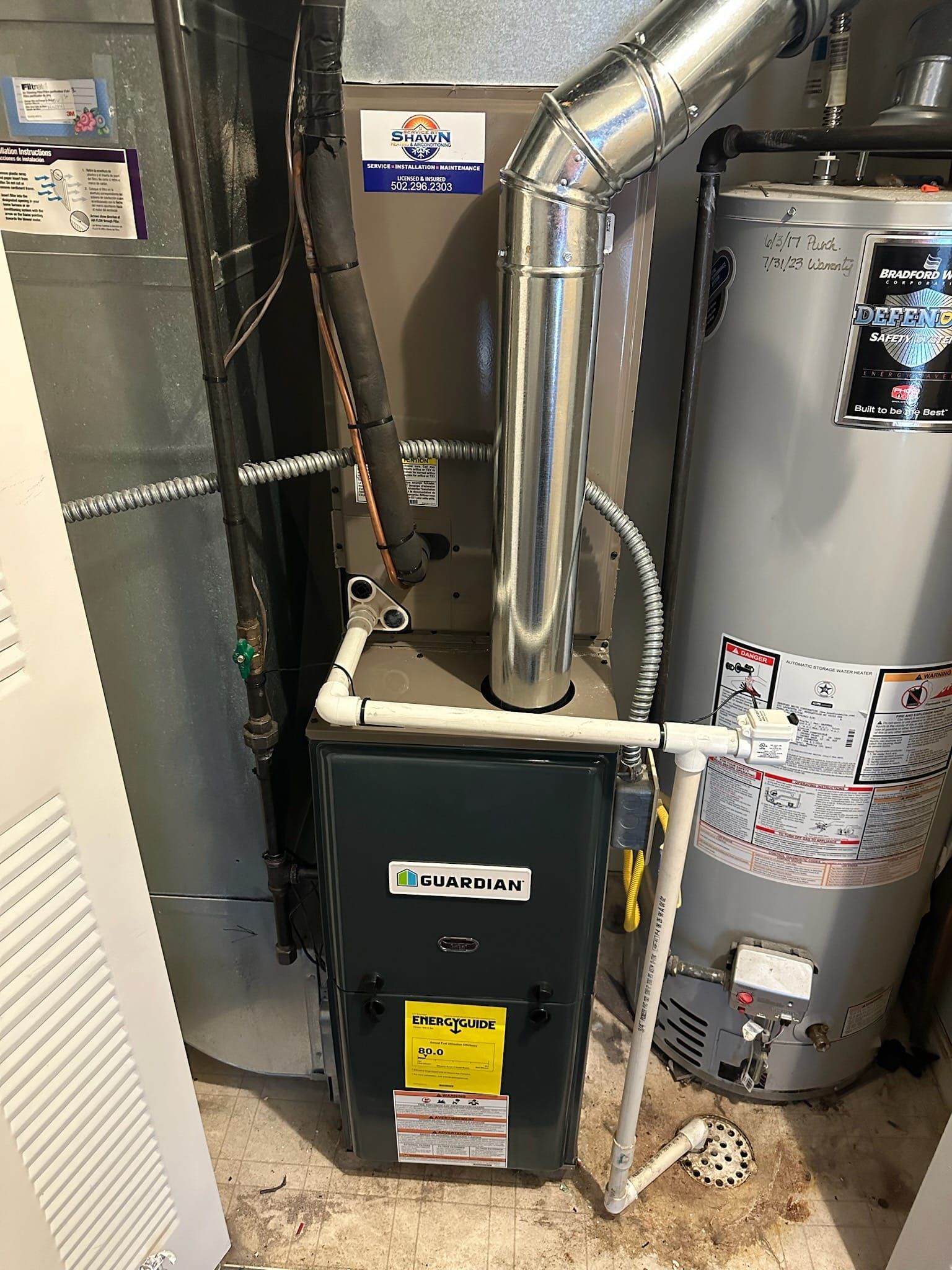 A gas heater is sitting next to a water heater in a basement.