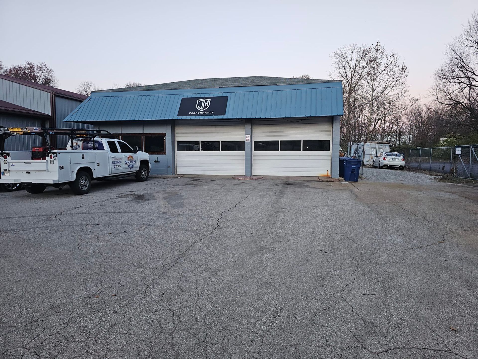 Two white trucks are parked in front of a building with a blue roof