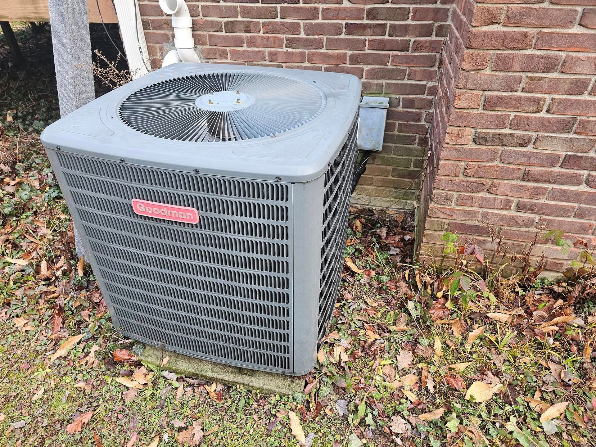An air conditioner is sitting on the side of a brick building.