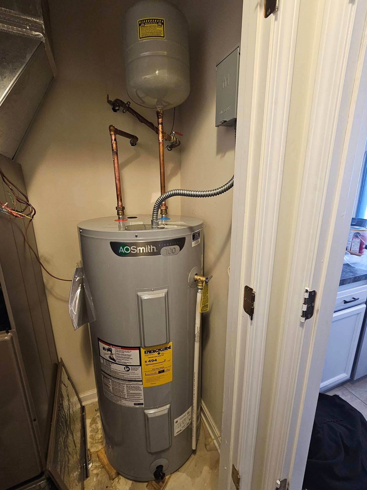 A water heater is sitting in a closet next to a door.