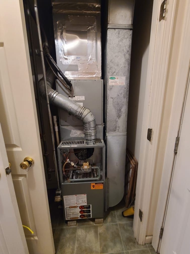 A furnace is sitting in a closet next to a door.