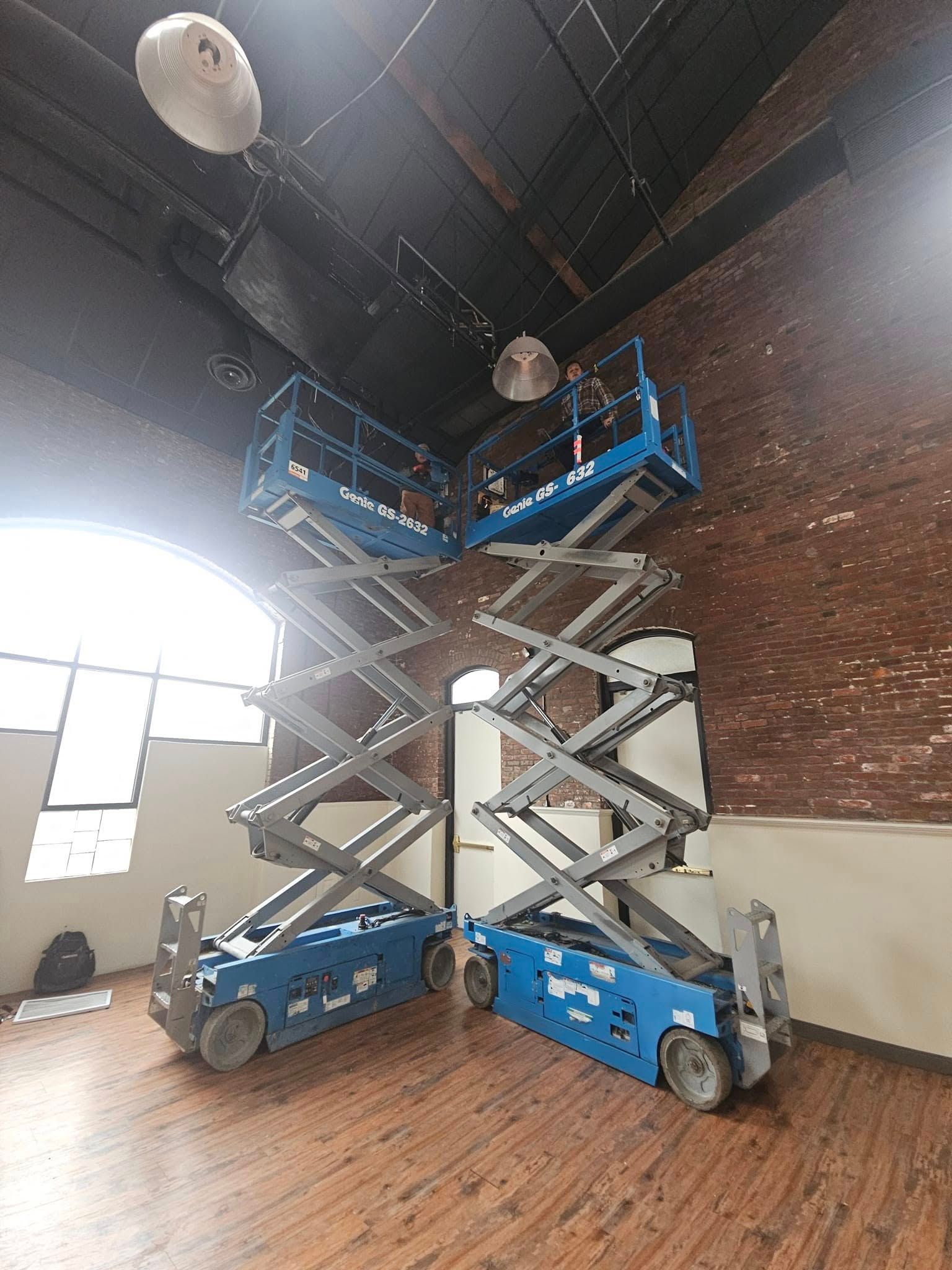 Two scissor lifts are sitting next to each other in a room.