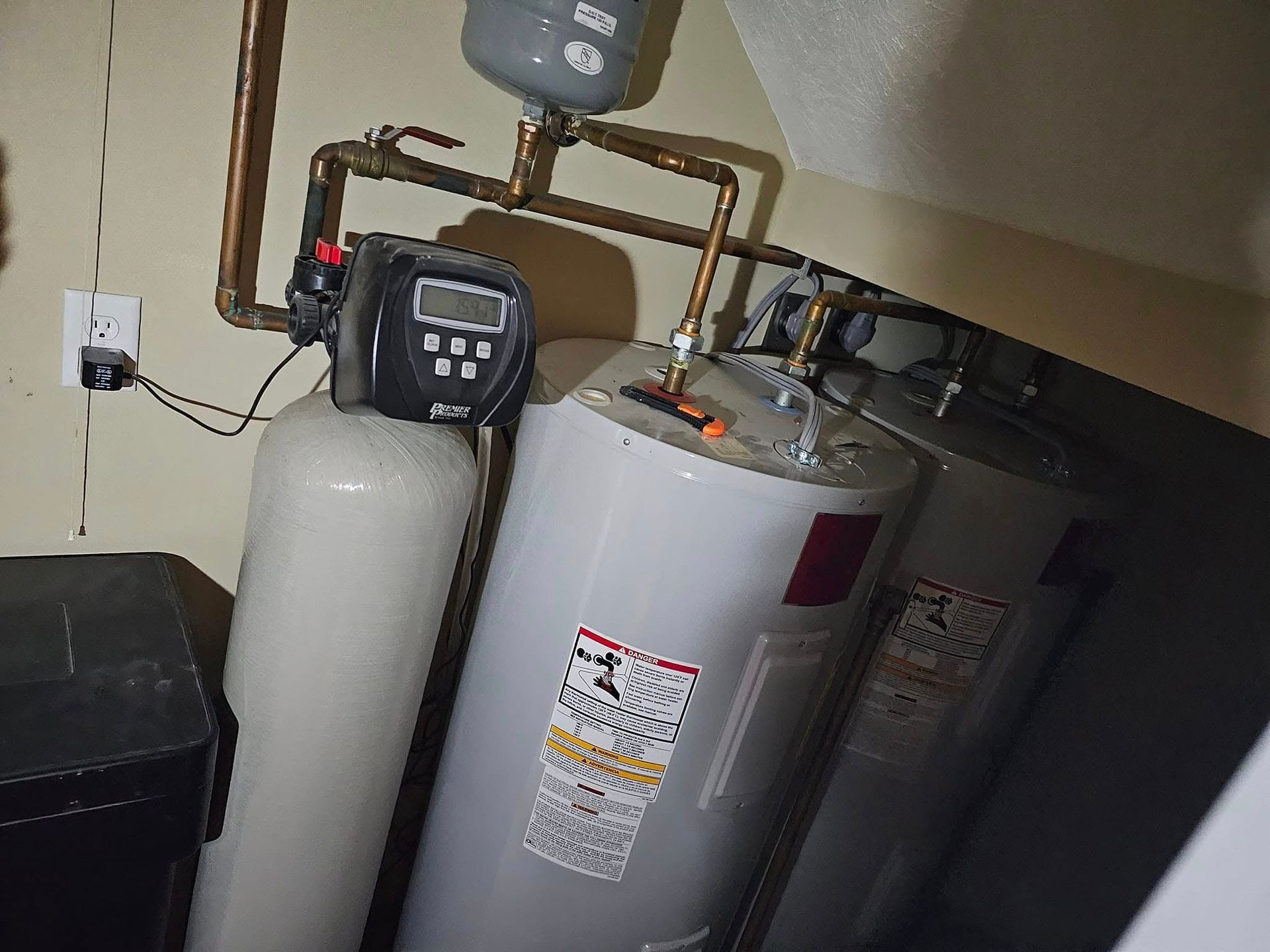 Three water heaters are sitting next to each other in a basement.