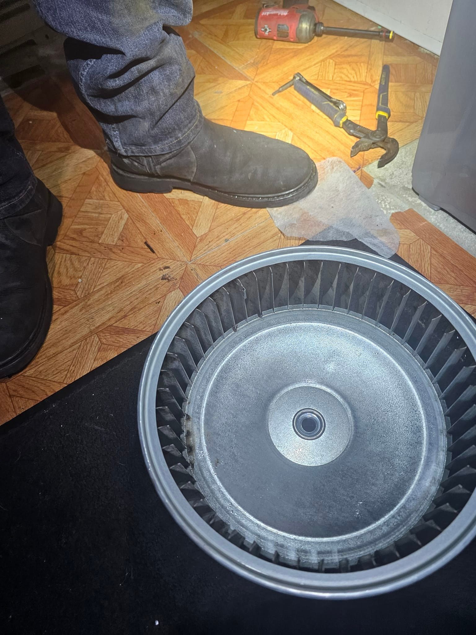 A person is standing next to a fan on the floor.