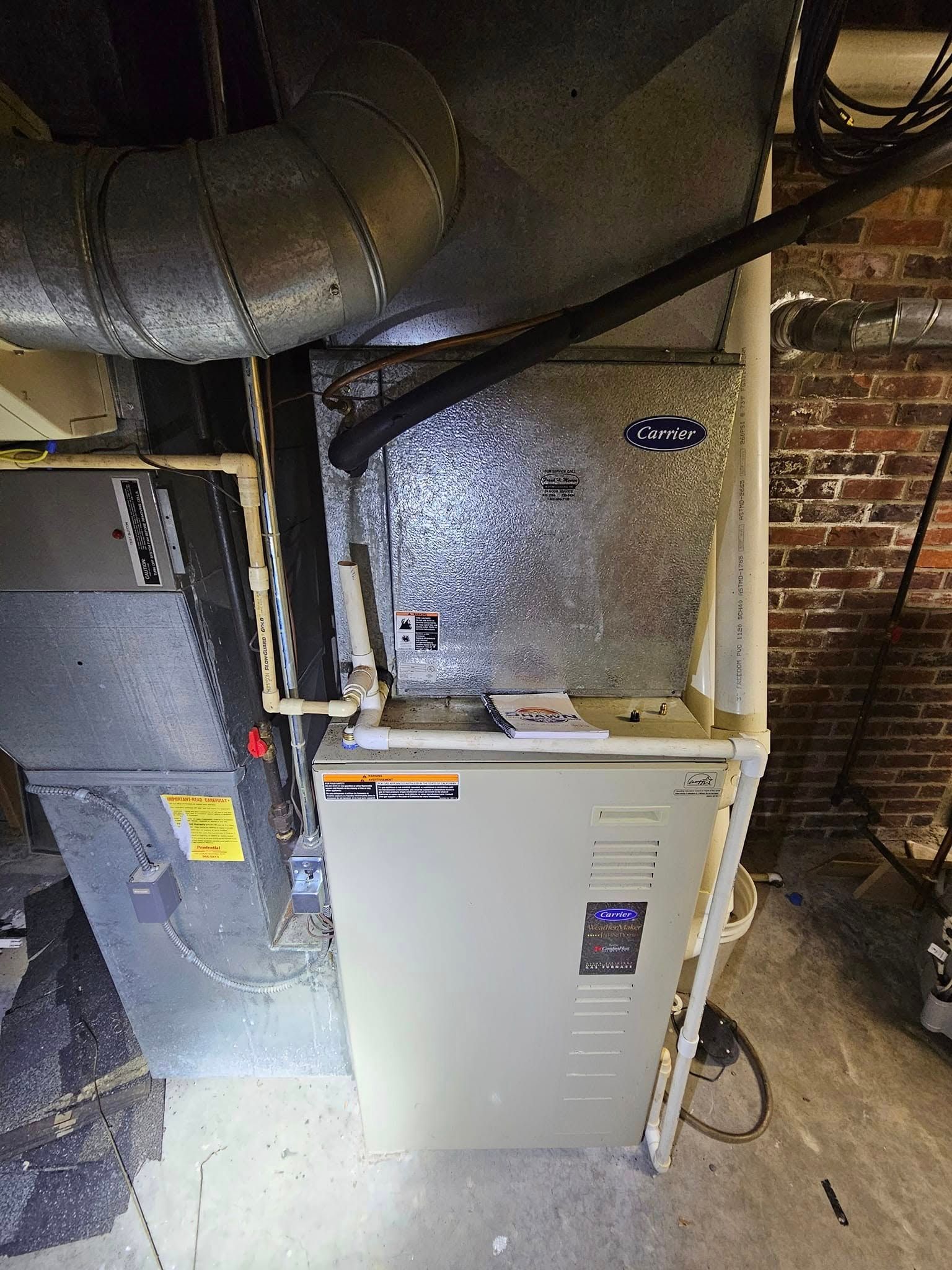 An air conditioner is sitting in a basement next to a brick wall.
