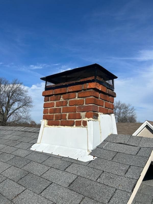 A brick chimney is sitting on top of a roof.