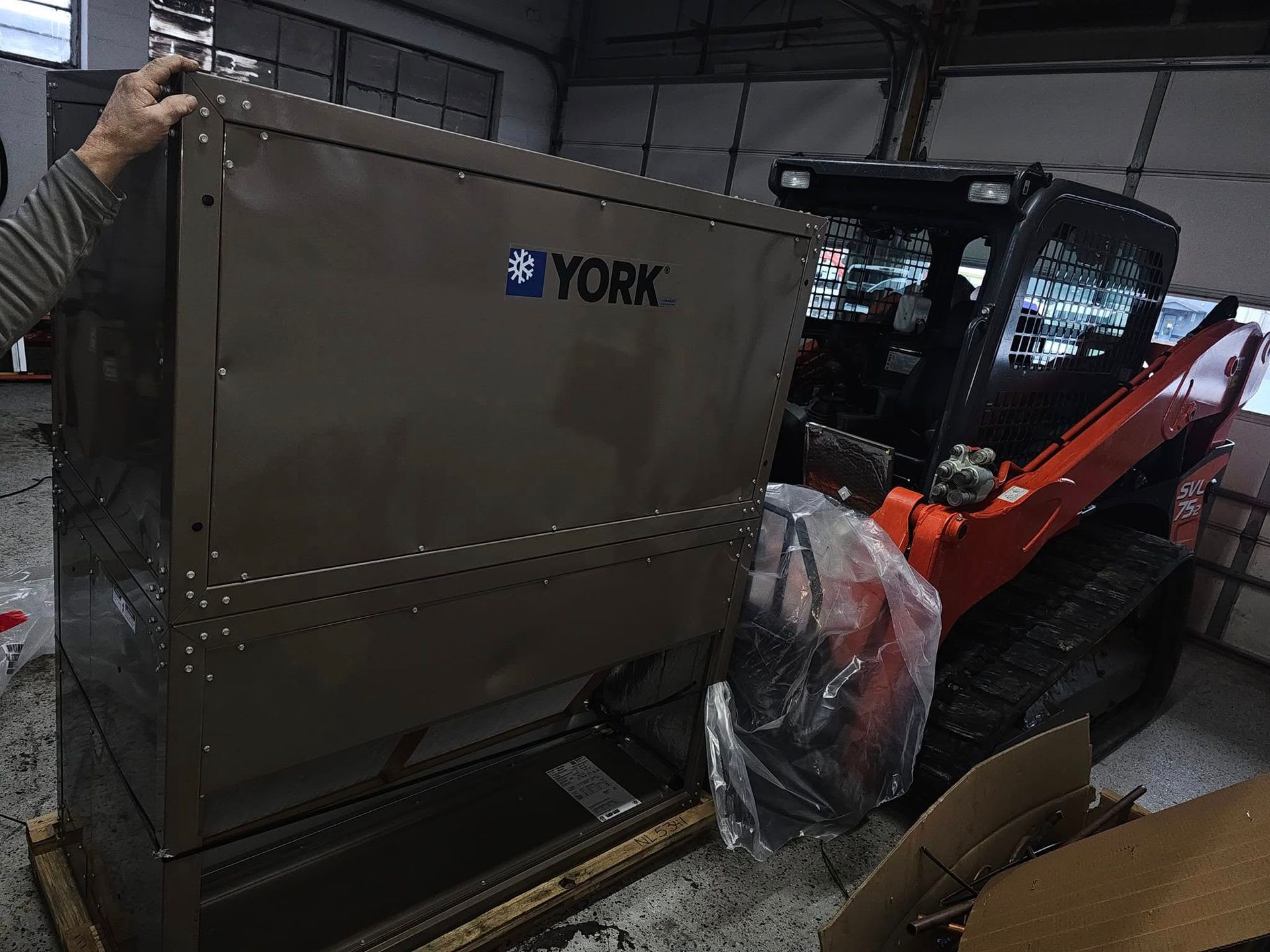 A man is standing next to a york machine in a garage.