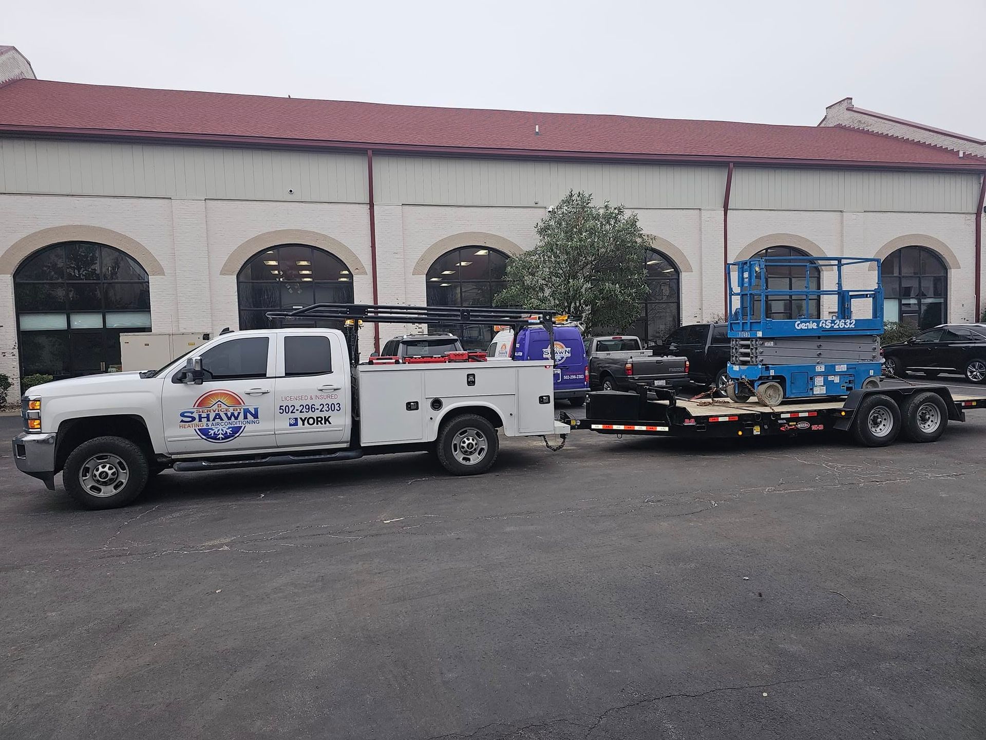 A white truck with a trailer attached to it is parked in front of a building.