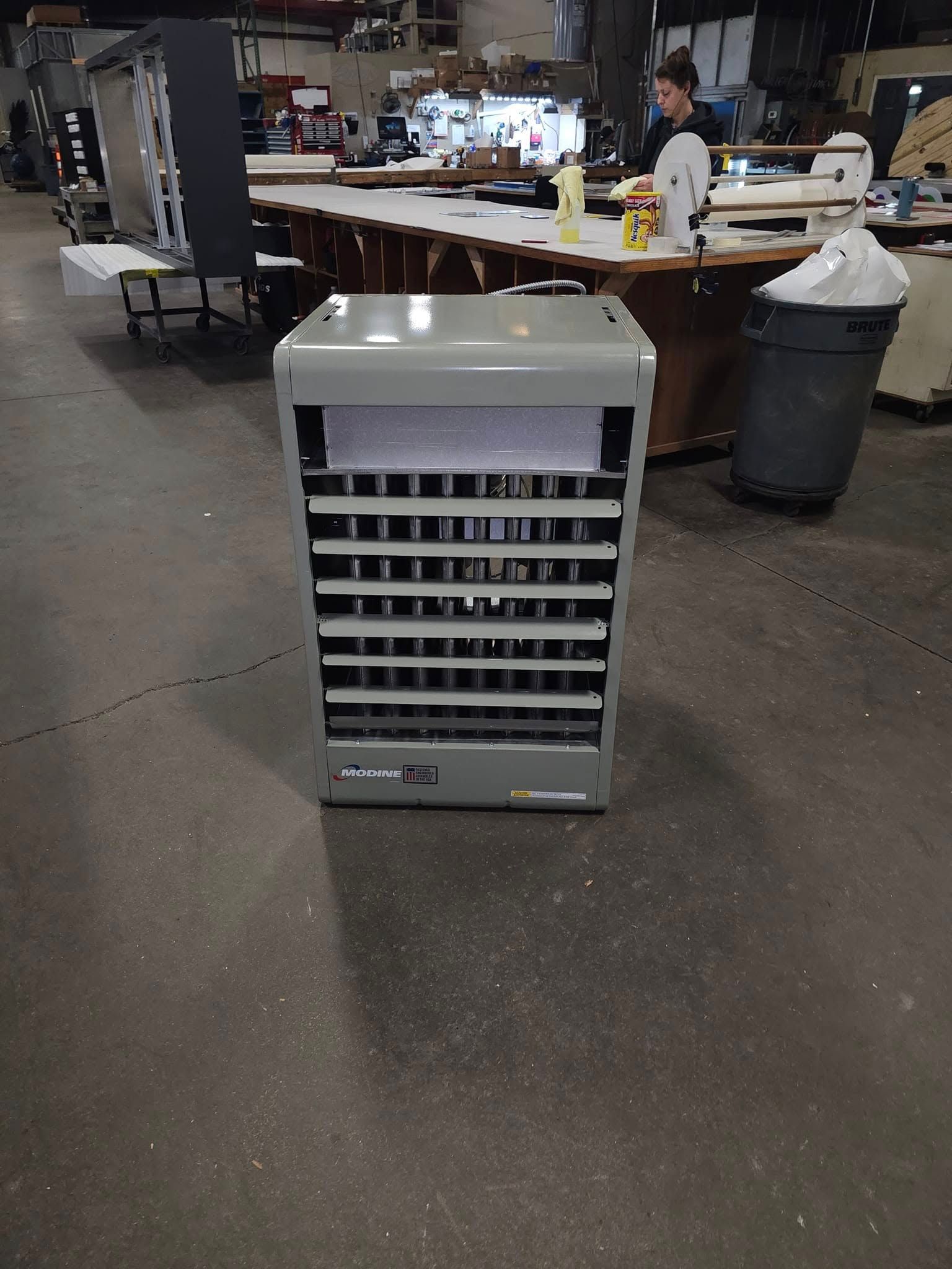 A large heater is sitting on the floor in a warehouse.