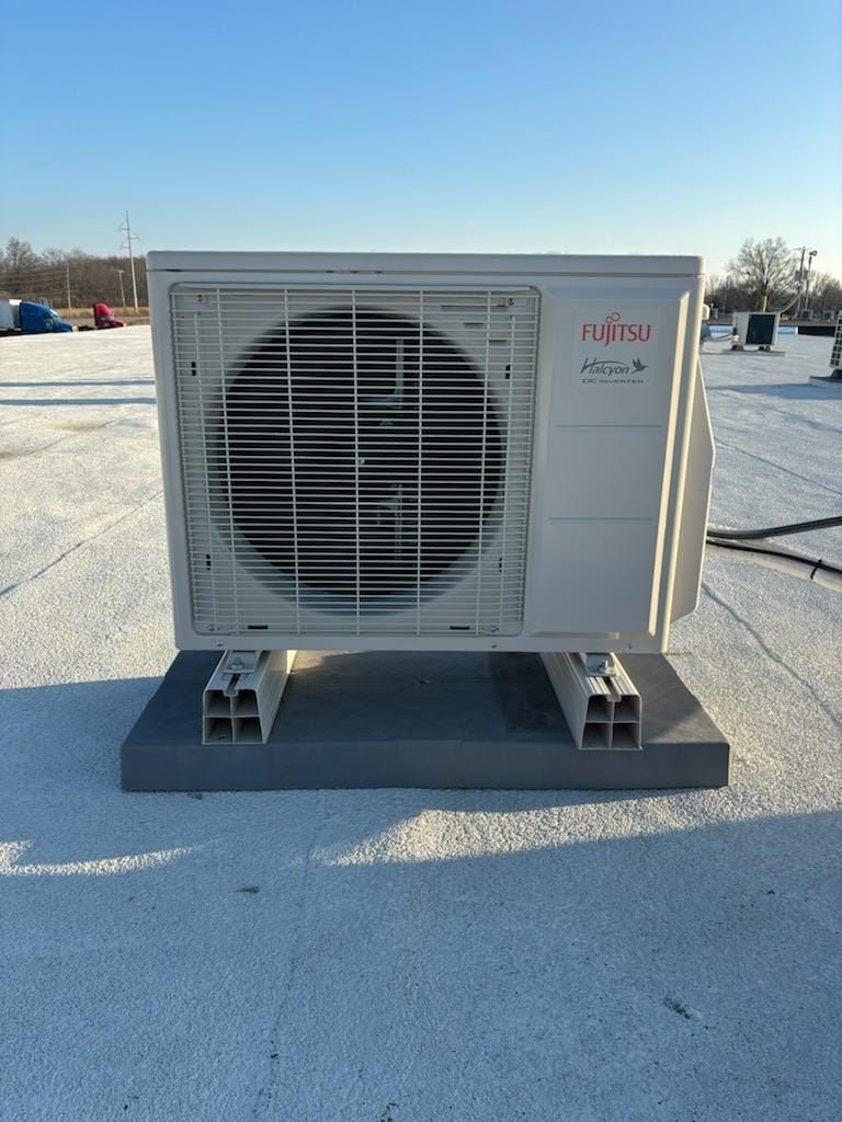 A fujitsu air conditioner is sitting on top of a white roof.