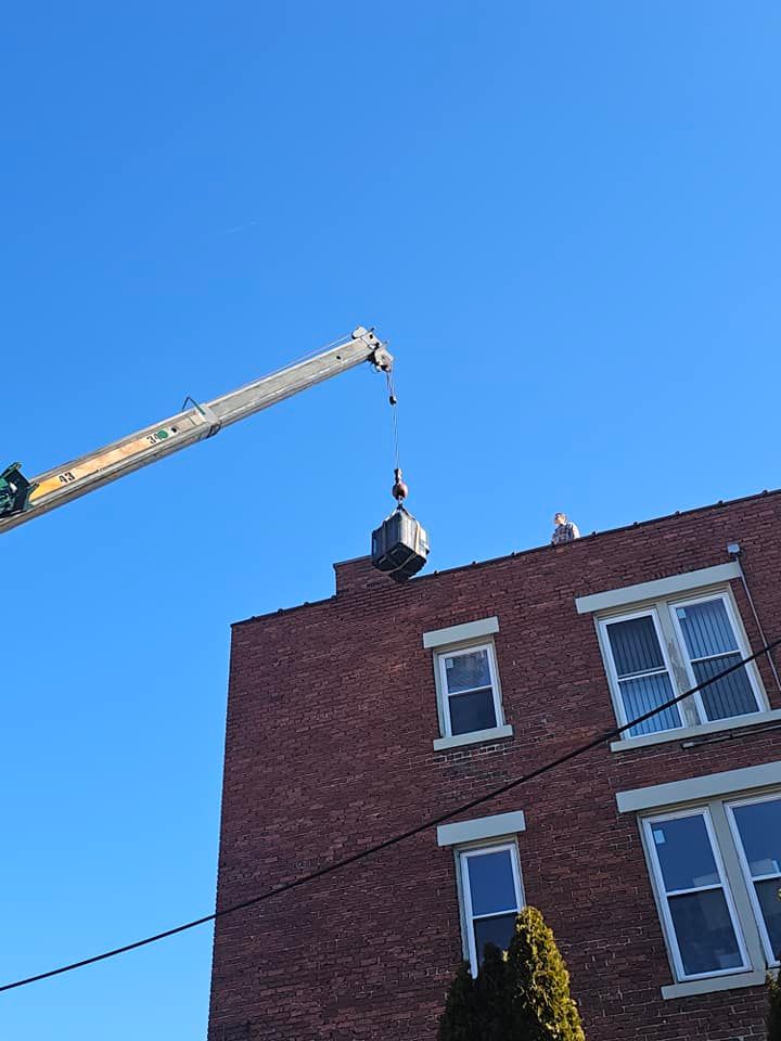 A crane is lifting a box on top of a brick building.
