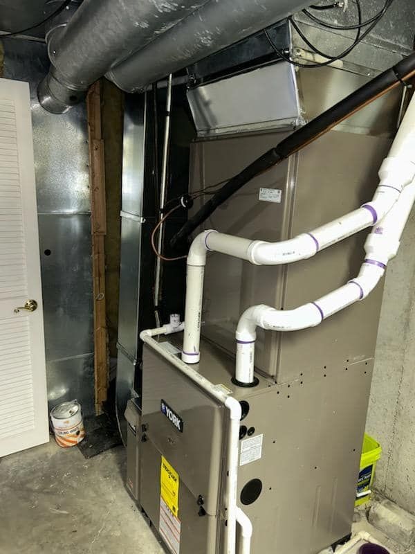 A basement with a furnace and pipes coming out of it.