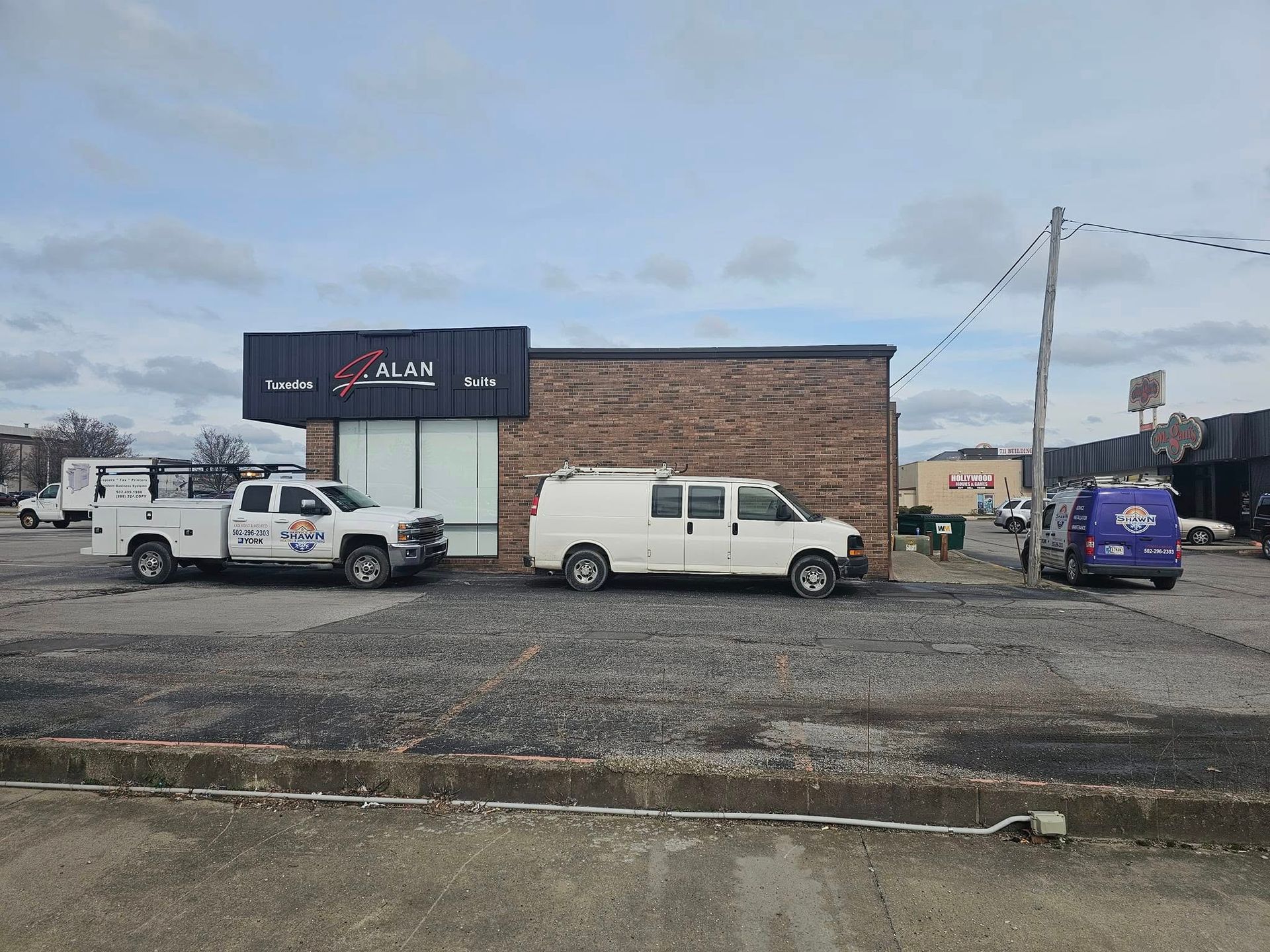Two white vans are parked in front of a brick building.