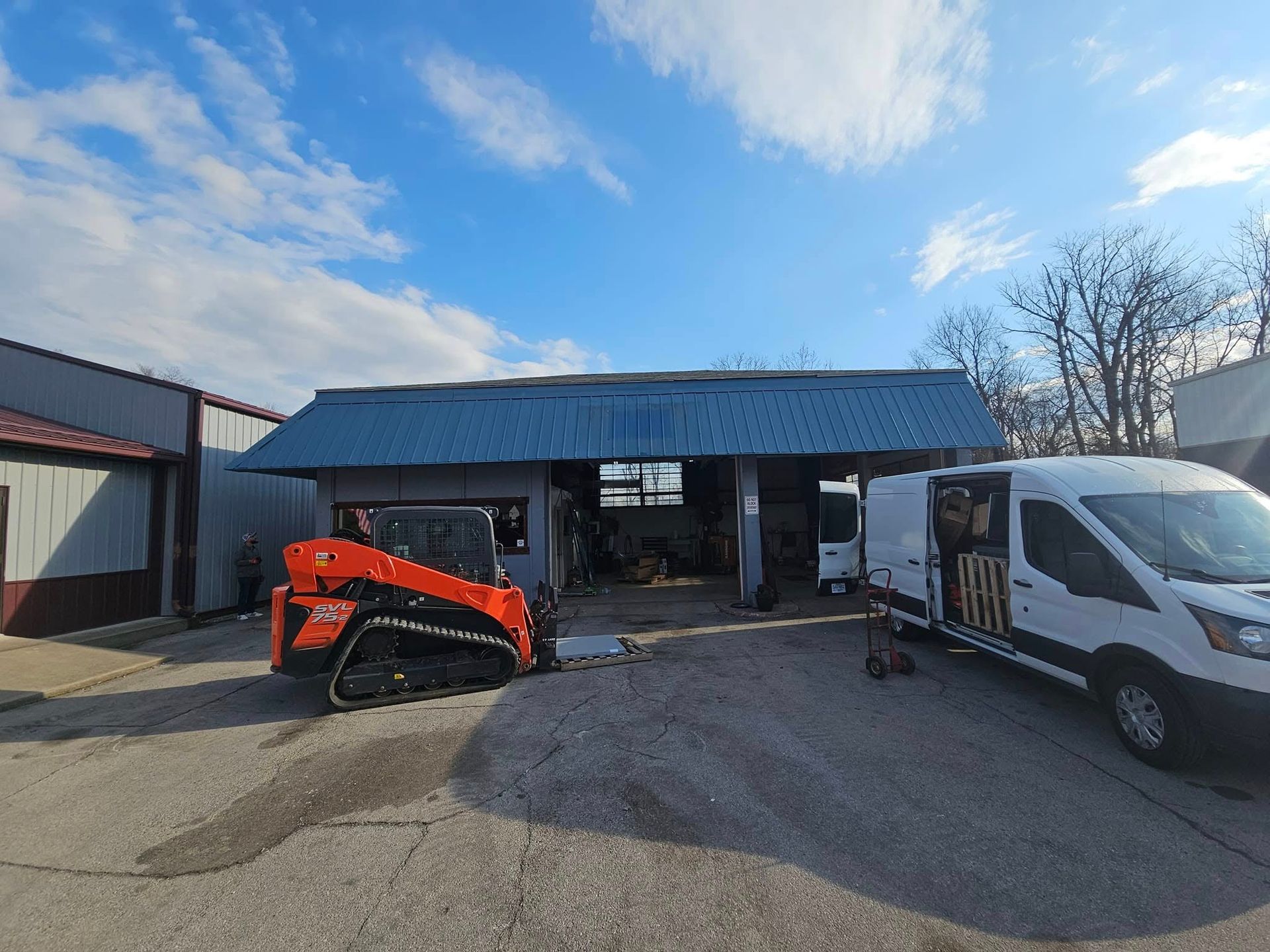 A bulldozer and a van are parked in front of a building.