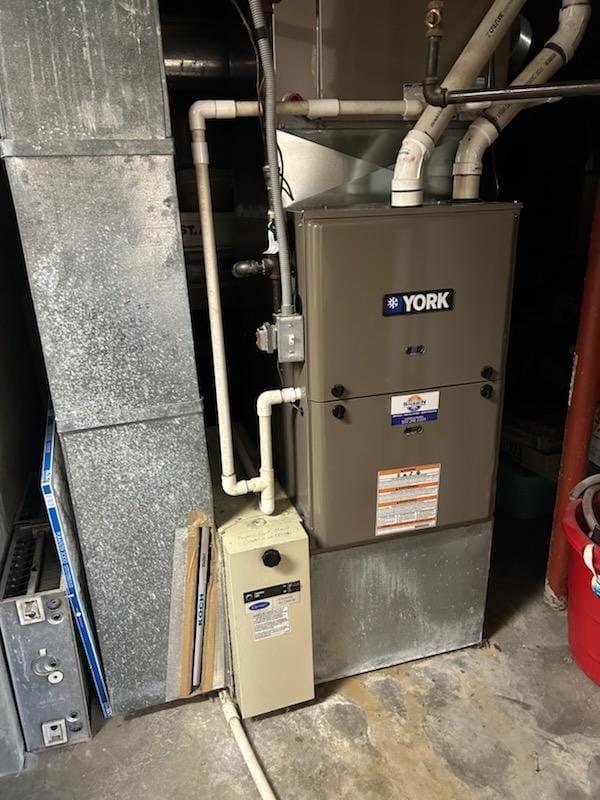 A york air conditioner is sitting in a basement next to a wall.