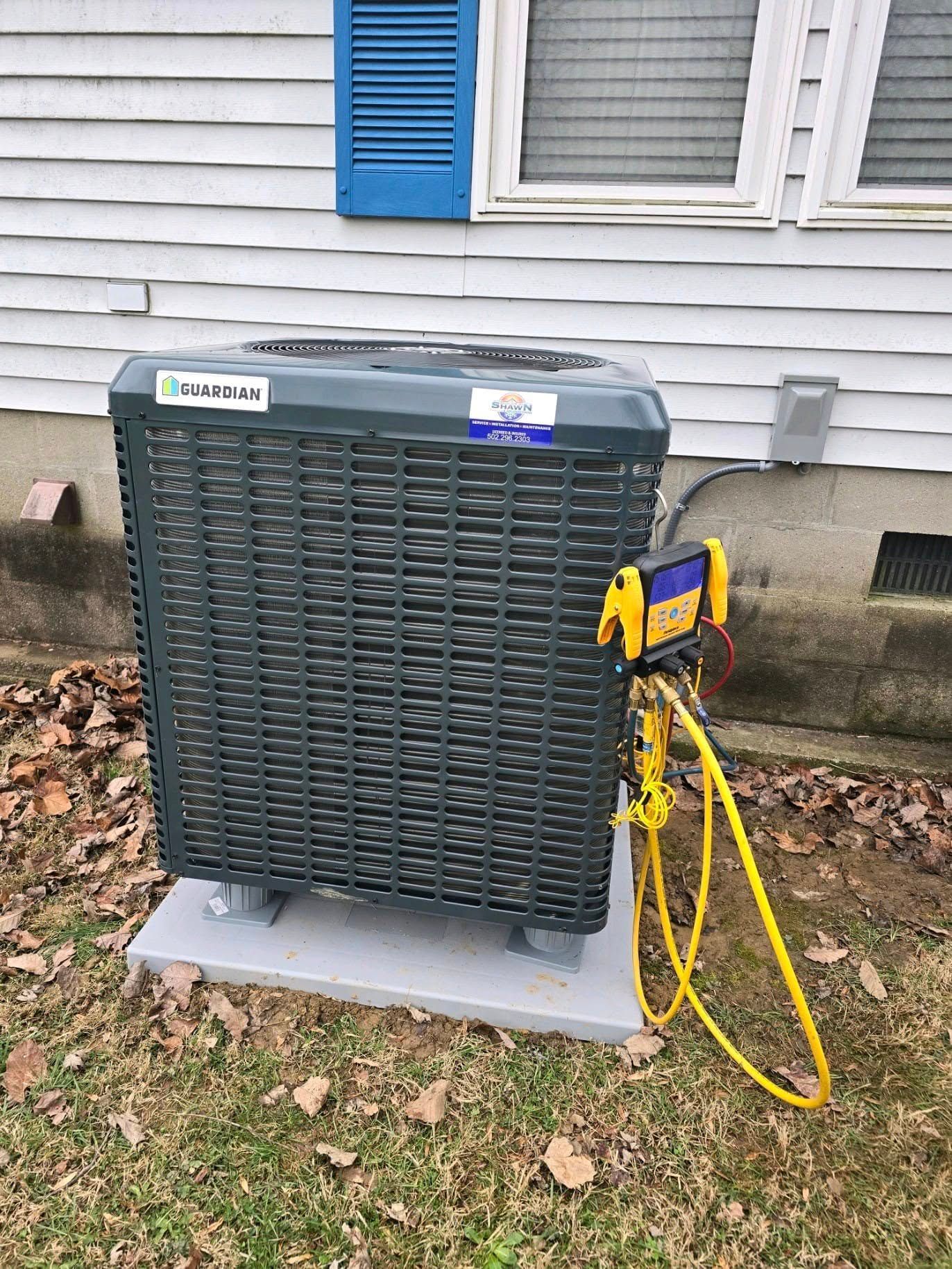 An air conditioner is sitting on top of a concrete platform in front of a house.