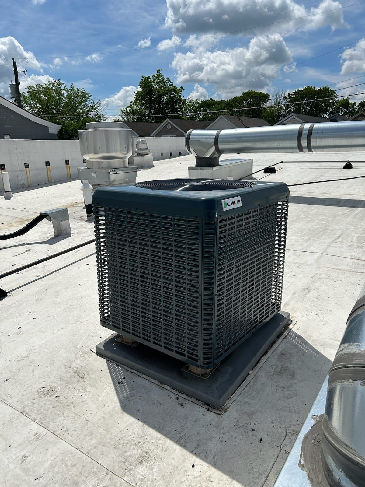 A large air conditioner is sitting on top of a white roof.
