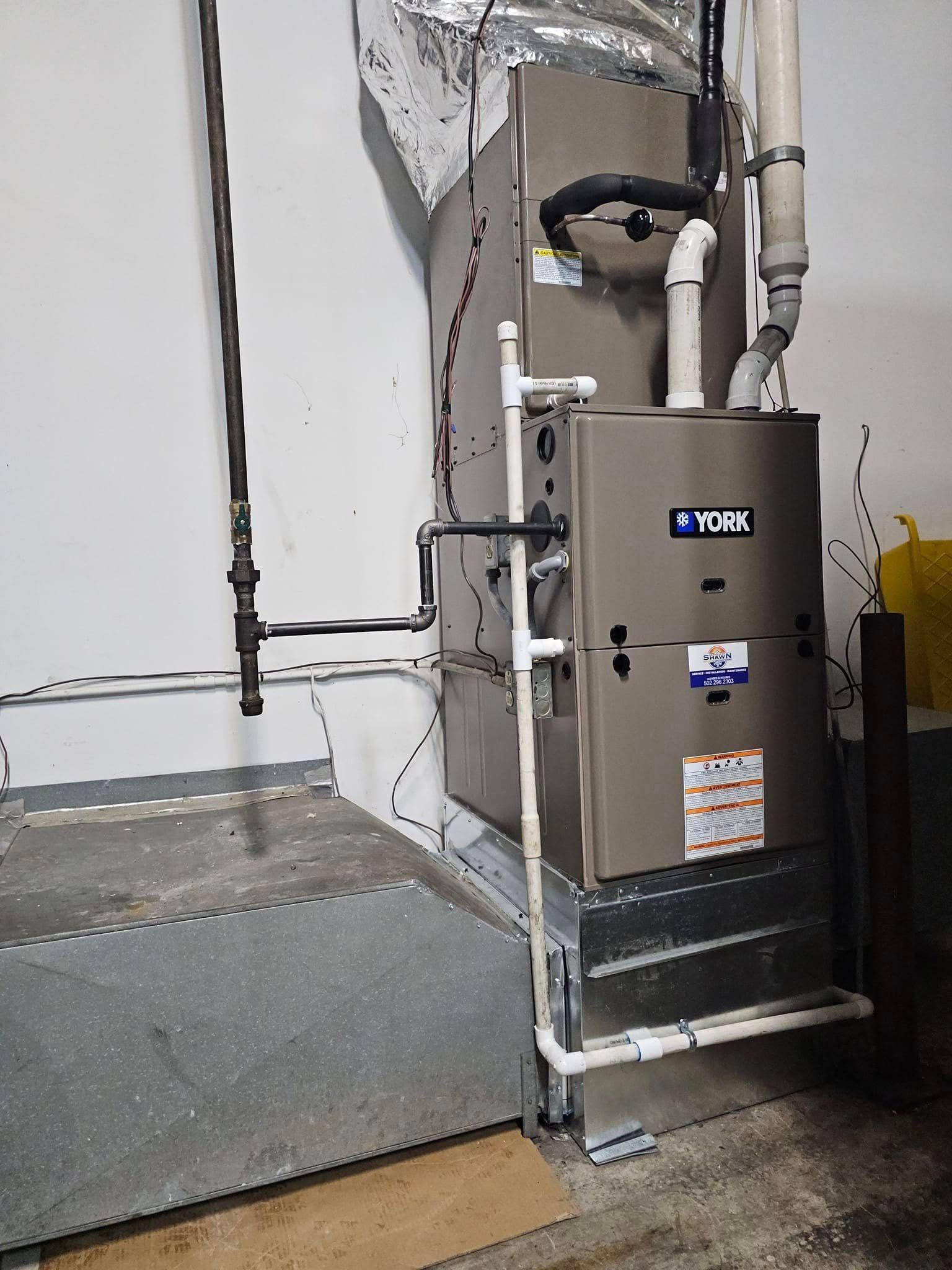 A york air conditioner is sitting in a basement next to a wall.