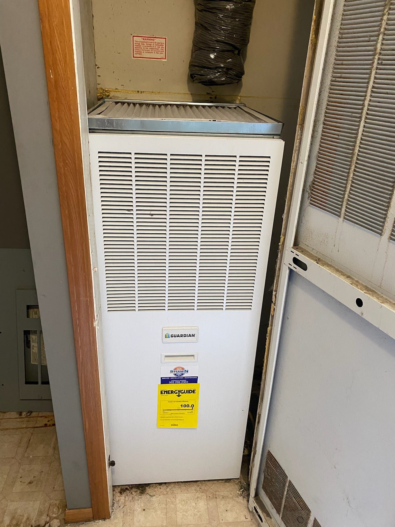 A white air conditioner is sitting in a corner of a room.