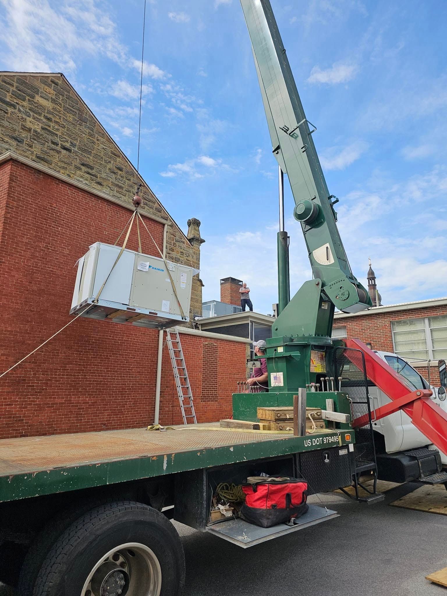 A truck with a crane on the back of it is parked in front of a brick building.