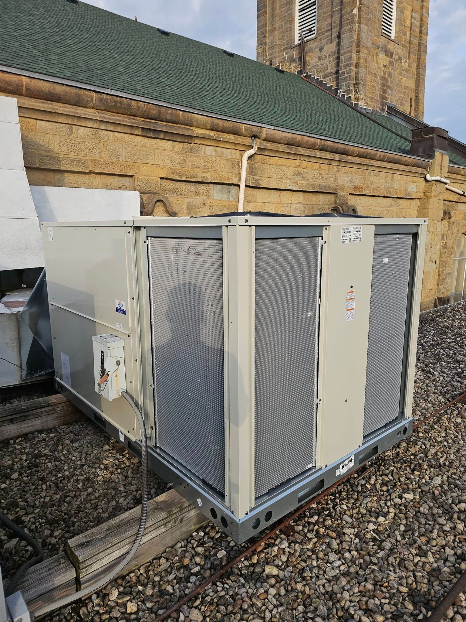 A large air conditioner is sitting on the roof of a building.
