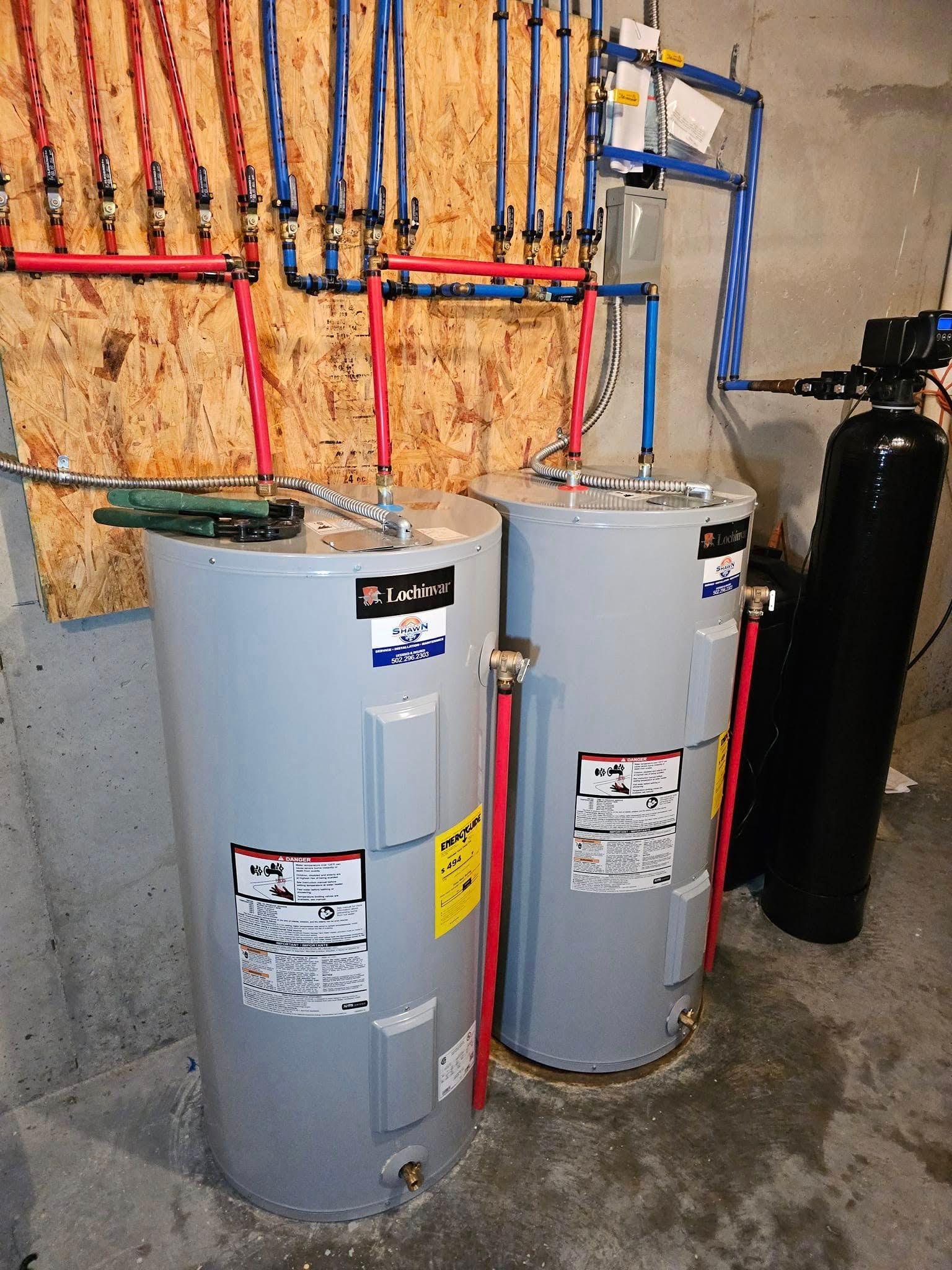 Two water heaters are sitting next to each other in a basement.